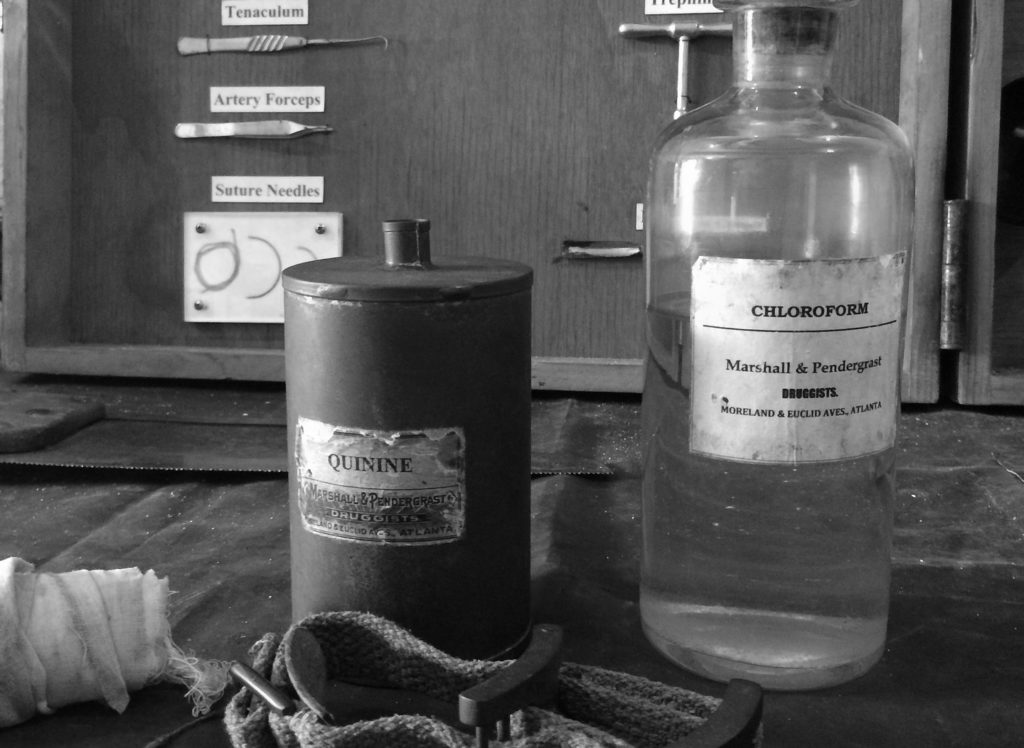 Symbolbild für "Mutterschoß": Foto mit altertümlichem Medizinbesteck und Medikamentflaschen u.a. mit Chloroform in schwarz/weiß